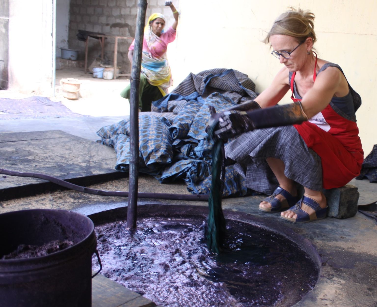 Artist dyeing stoles in indigo vat at bagru block printed workshops jaitexart 